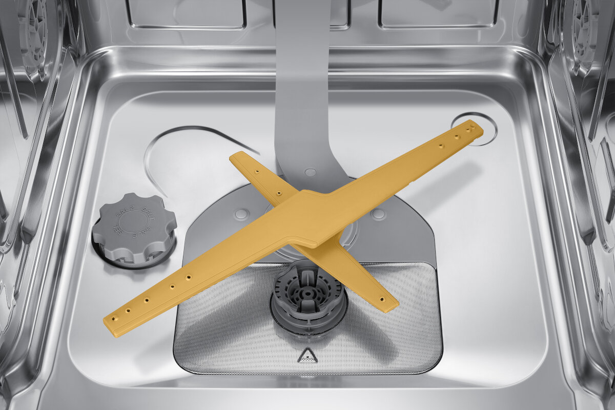 Wnętrze zmywarki, pusty dolny kosz z żółtym ramieniem spryskującym. Srebrne wnętrze, dobrze oświetlone.