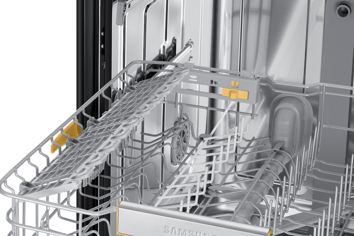 Otwarty wnętrze zmywarki. Srebrne metalowe stojaki z żółtymi i pomarańczowymi regulowanymi częściami.
