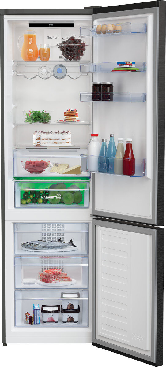 Lodówka z otwartymi drzwiami, wypełniona żywnością. Zawiera owoce, jajka, ciasta i napoje.