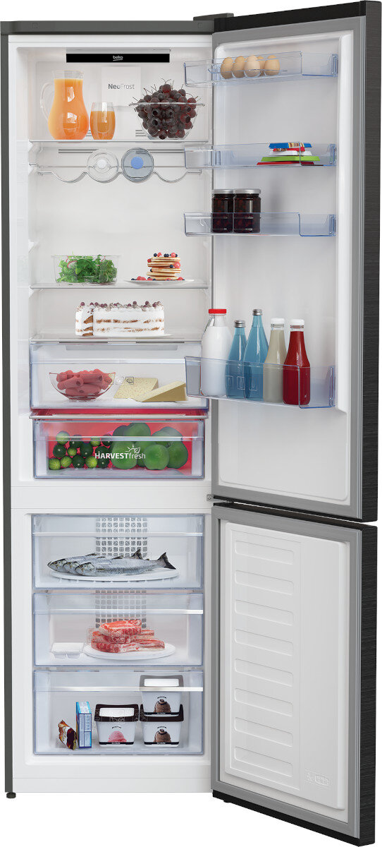 Lodówka z otwartymi drzwiami, pokazująca półki z produktami spożywczymi, w tym ciastami, warzywami i napojami.