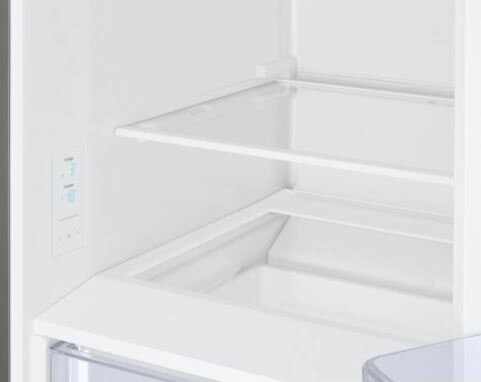 Widok wnętrza białej lodówki, pokazujący półki i przegródki do przechowywania.