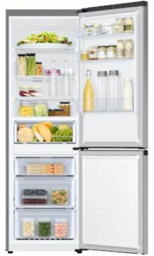 Otwarta lodówka, wypełniona jedzeniem. Górna połowa z półkami, dolna z szufladami. Srebrny wygląd zewnętrzny.