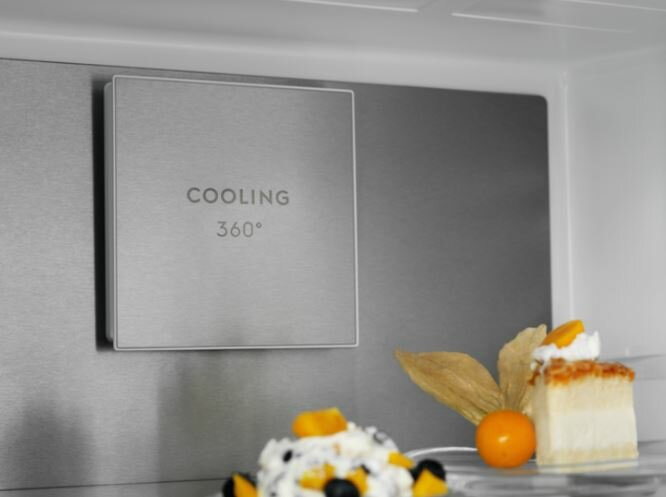 Zbliżenie wnętrza lodówki z systemem chłodzenia i deserami wystawionymi na półce.