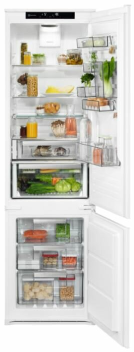 Biała lodówka z otwartymi drzwiami. W środku znajdują się półki z produktami spożywczymi, w tym warzywami.