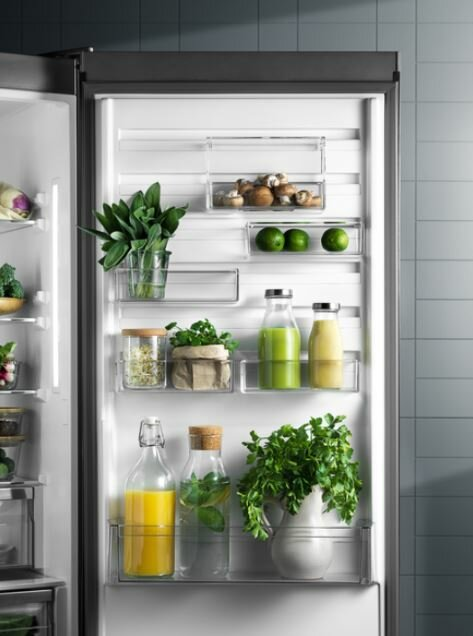 Półki lodówki ze świeżymi produktami i napojami. Zawiera zioła, owoce i butelki.