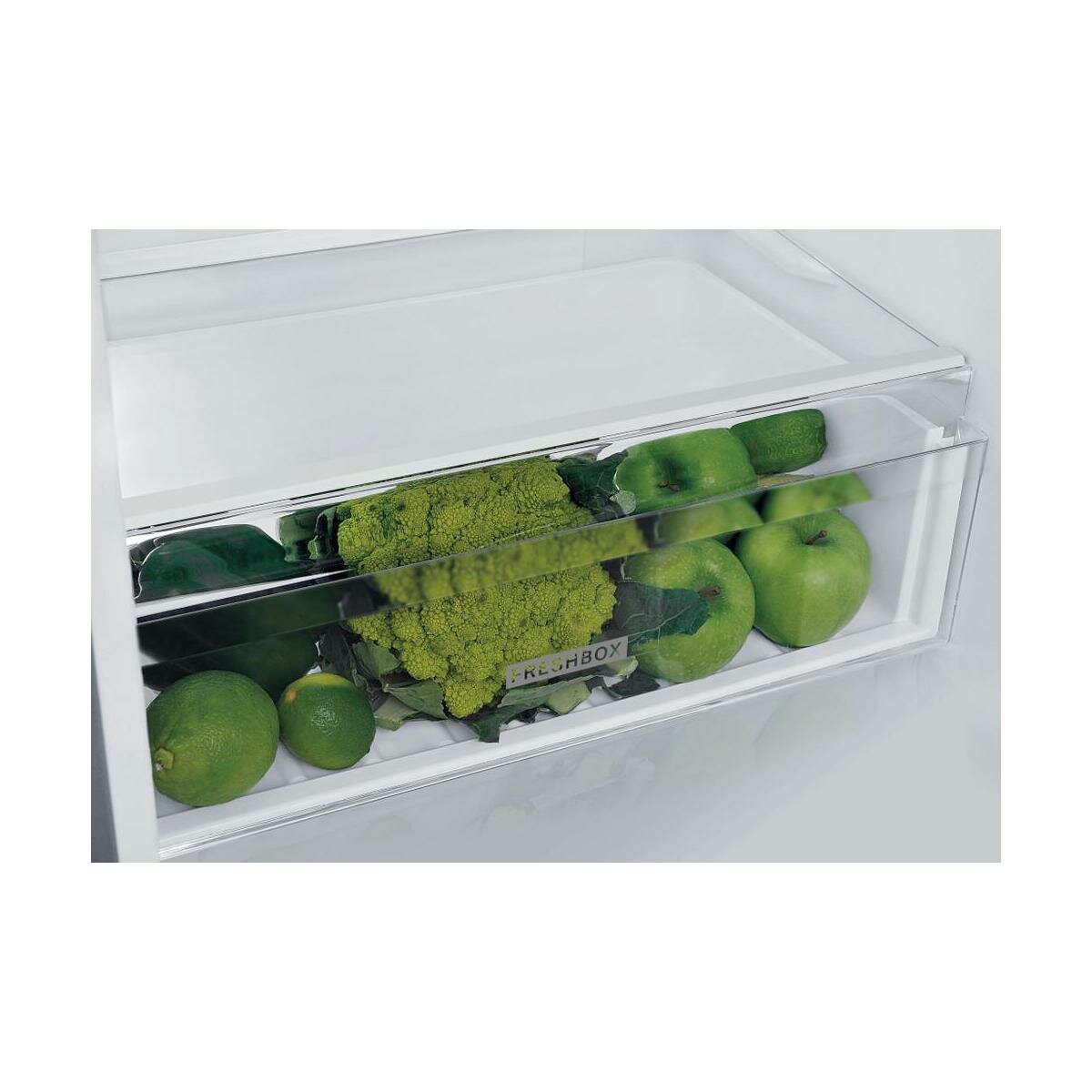 Zbliżenie szuflady lodówki z zielonymi jabłkami, limonkami, brokułami i sałatą.