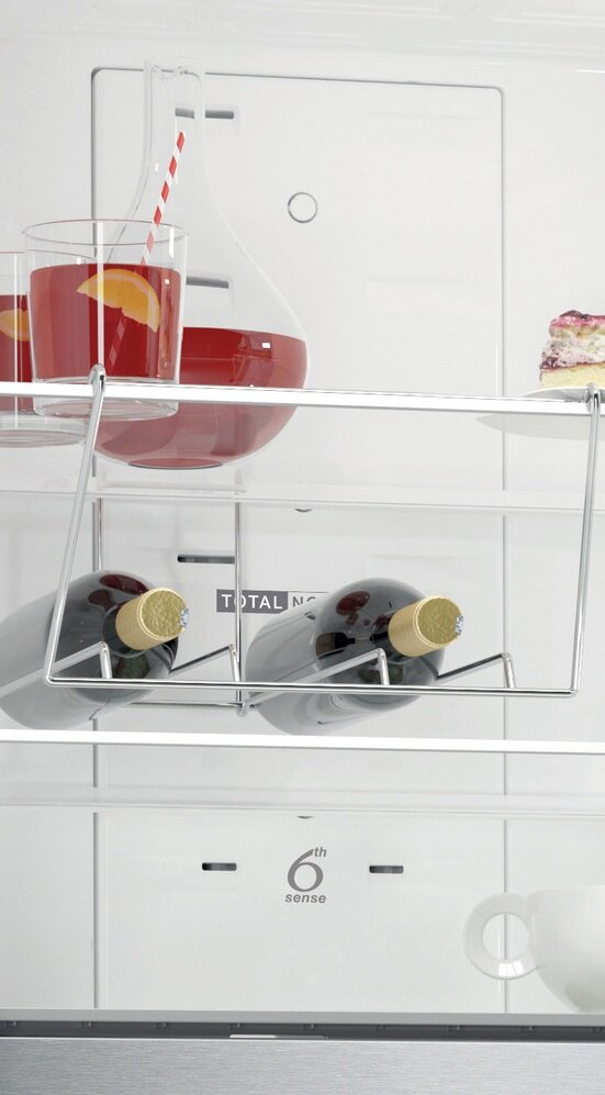 Wnętrze lodówki z butelkami wina, napojami i kawałkiem ciasta, z białym tłem.