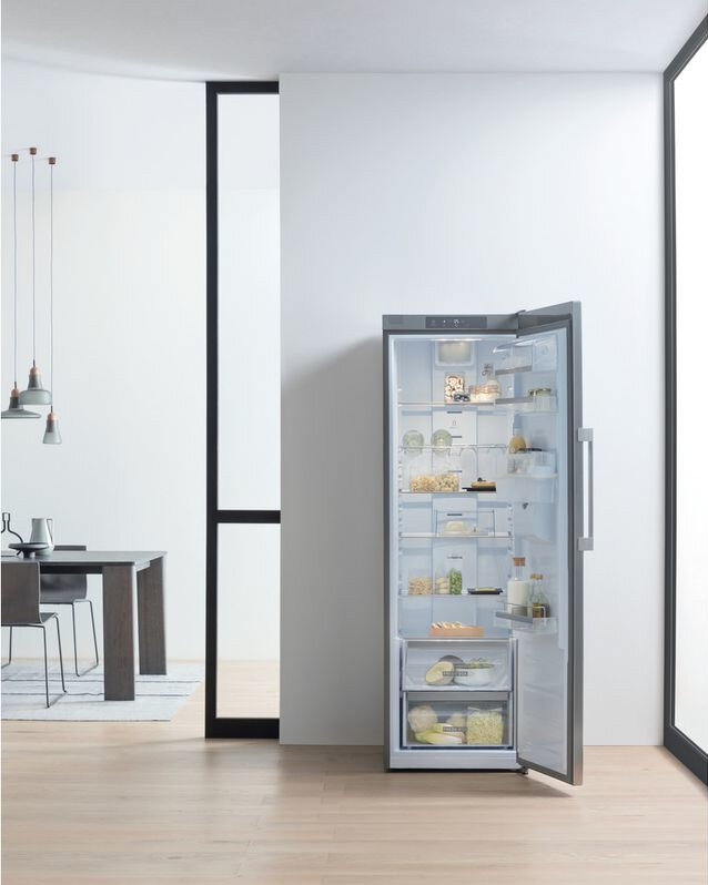 Otwarta lodówka z artykułami spożywczymi na półkach i w szufladach.