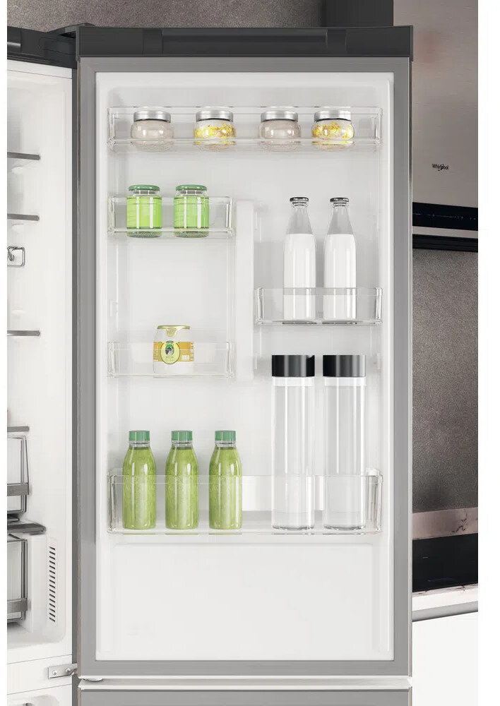 Wnętrze lodówki z półkami zawierającymi różne przedmioty, w tym słoiki, butelki i pojemniki.