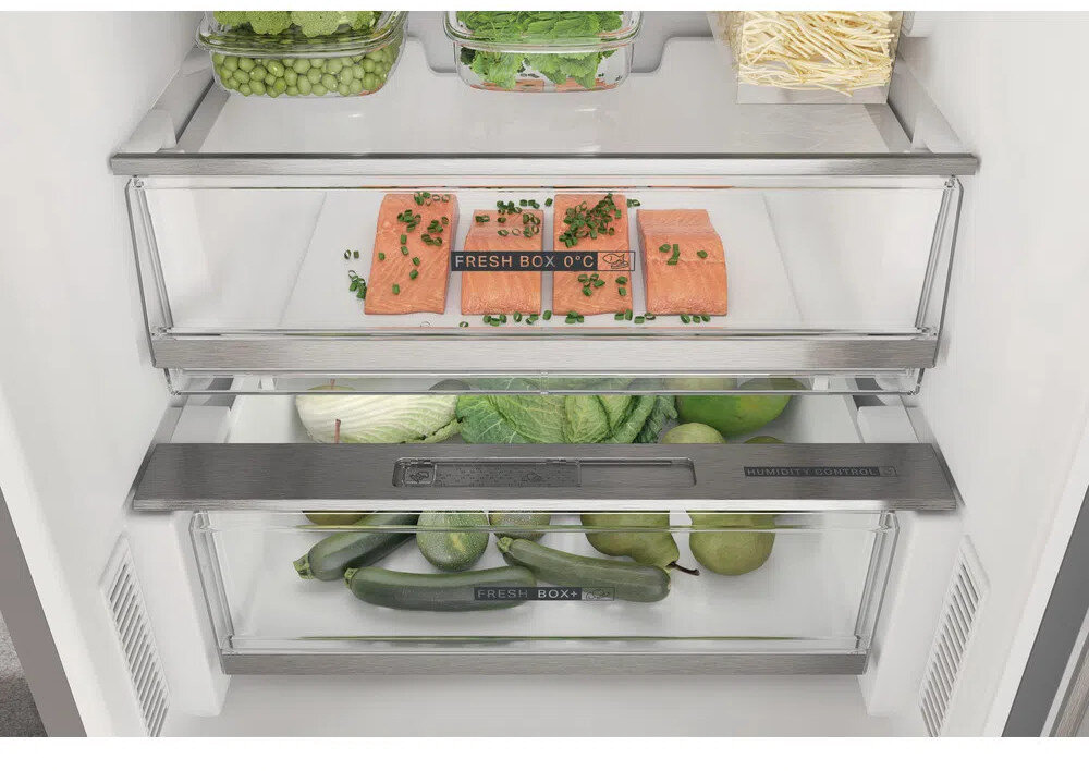 Zbliżenie wnętrza lodówki z świeżą żywnością w szufladach.