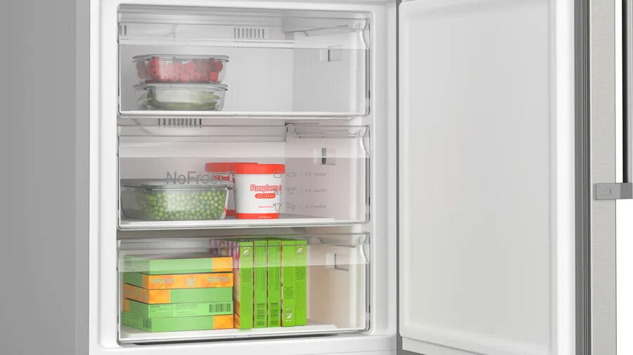 Otwarta komora zamrażarki, pokazująca szuflady z produktami spożywczymi, takimi jak jagody, groszek i mrożone posiłki.