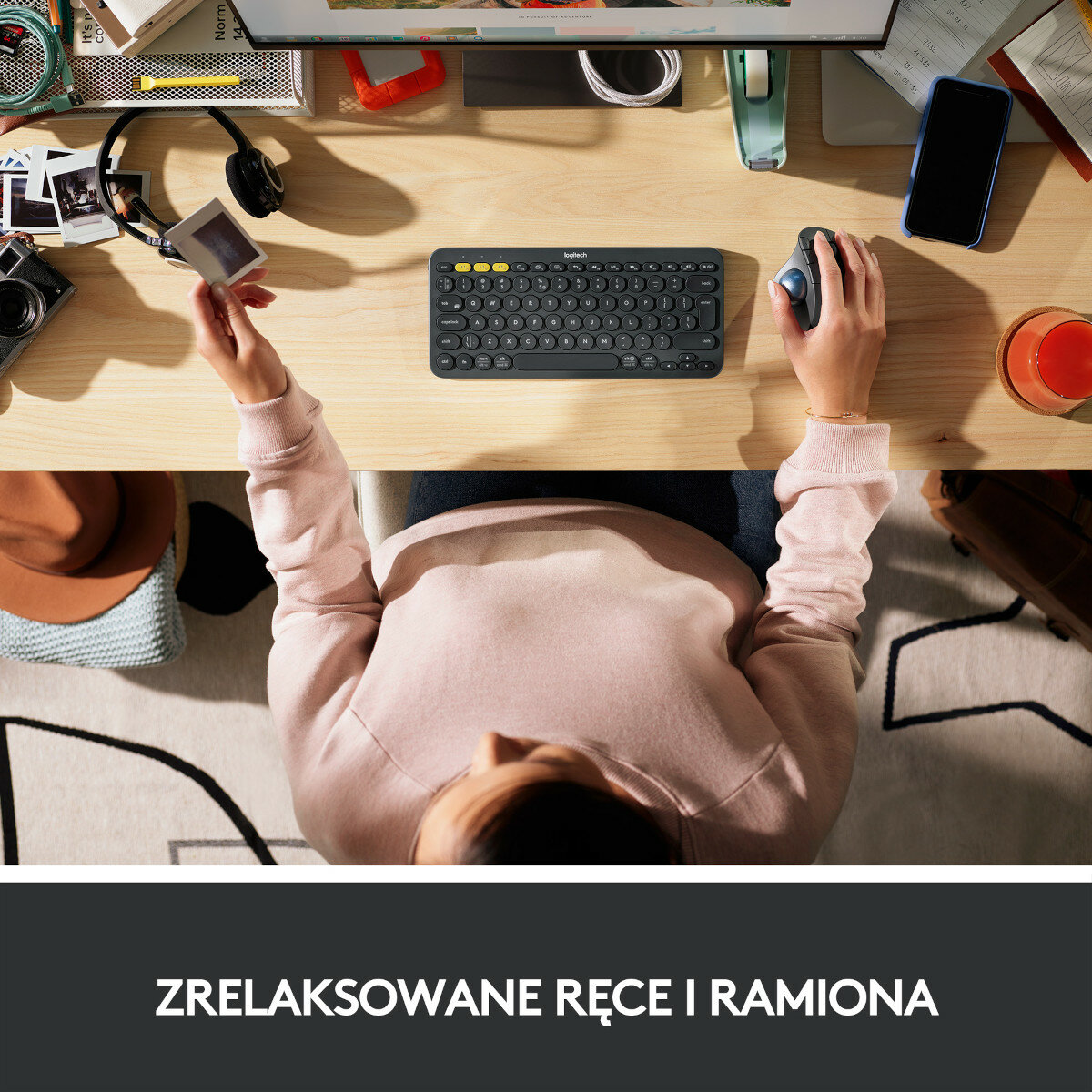 Osoba używająca klawiatury i myszy, z kubkiem i telefonem na biurku.