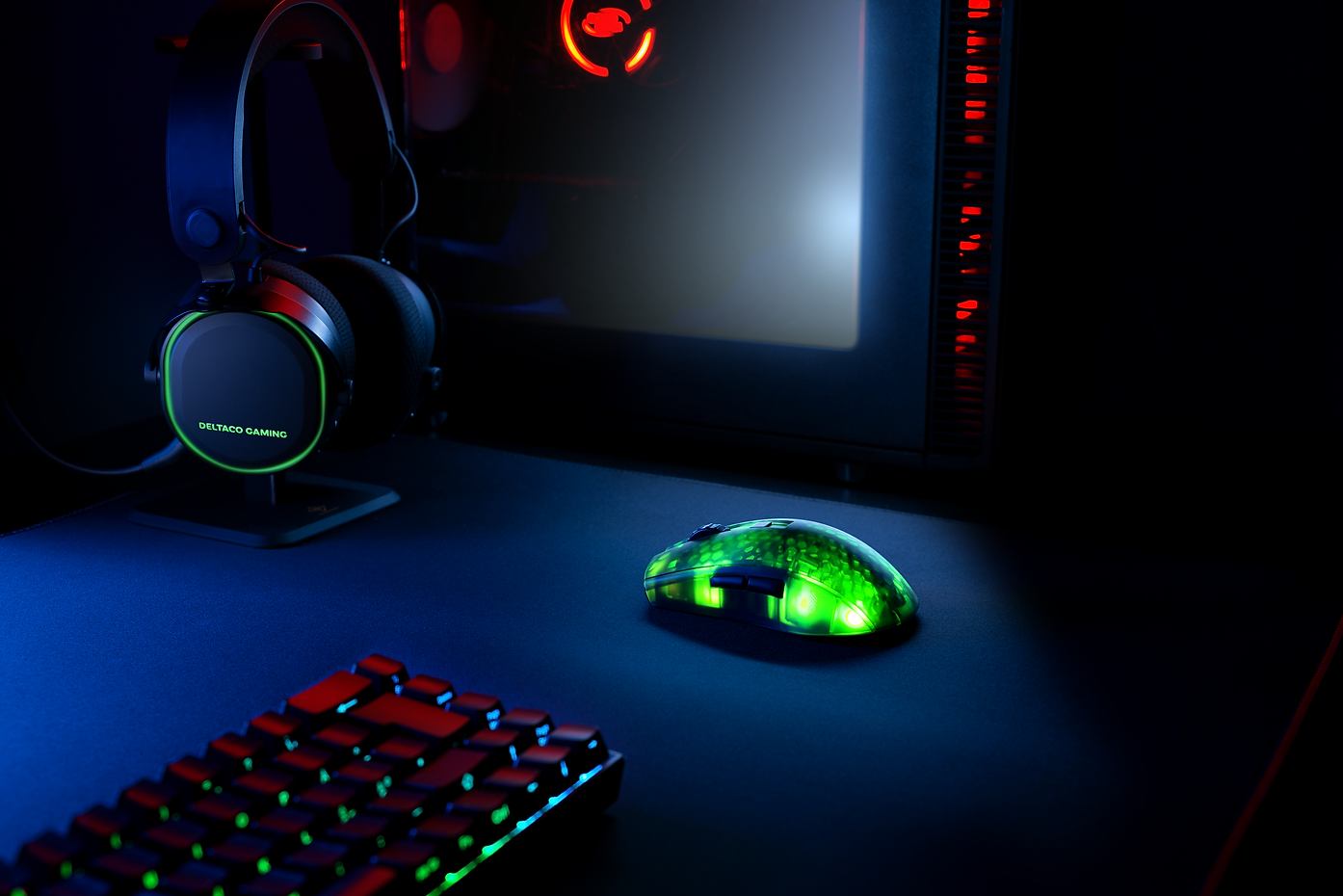 Gaming-Setup. Grün leuchtende Maus, Tastatur, Computer und Headset auf einem Schreibtisch.
