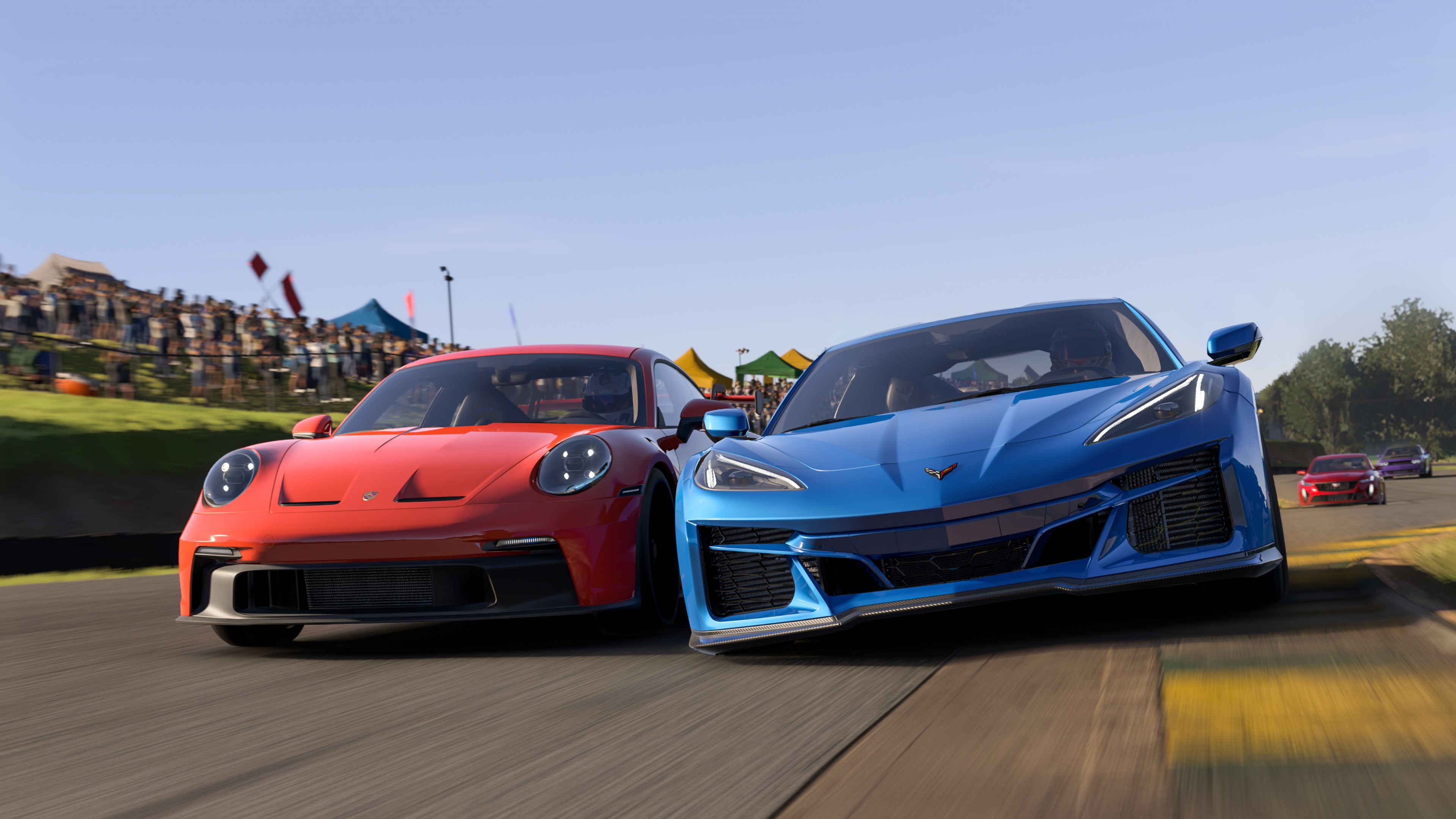Deux voitures de course sur une piste, une Porsche rouge et une Corvette bleue, avec foule en arrière-plan.
