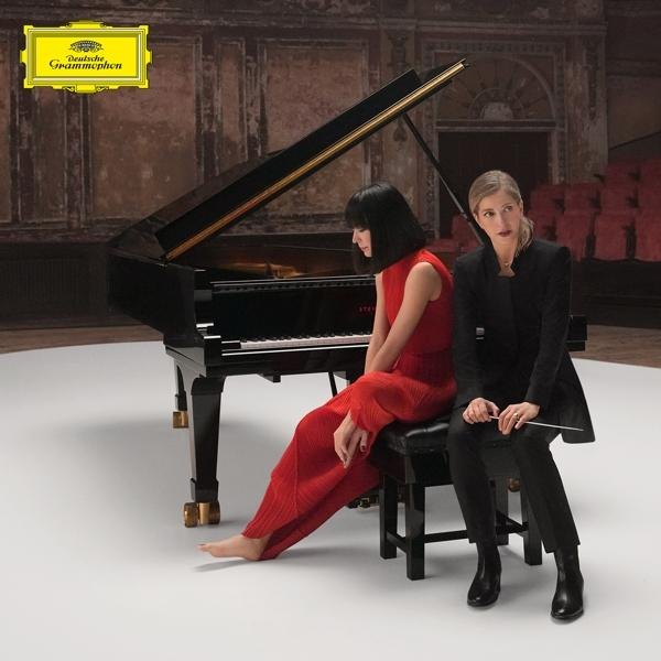 Zwei Frauen sitzen an einem Flügel. Eine in Rot, die andere in Schwarz. Deutsche Grammophon Logo sichtbar.