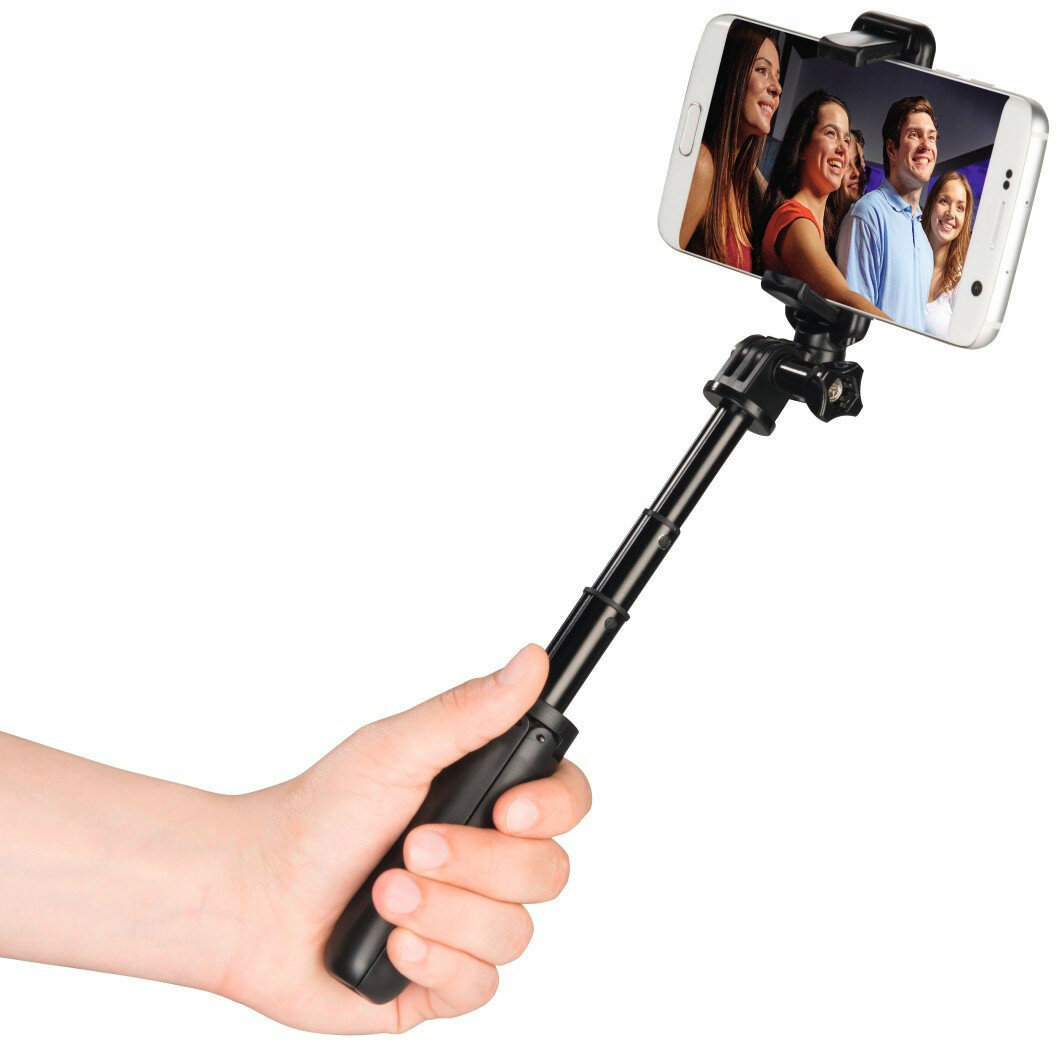 Ręka trzymająca kij do selfie z telefonem pokazującym zdjęcia uśmiechniętych ludzi.