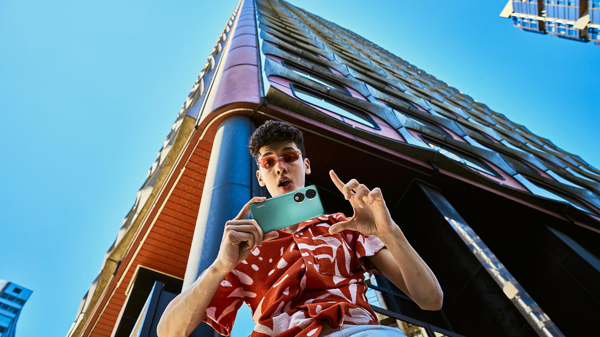 Mann im roten Hemd macht Foto mit grünem Telefon, niedriger Blickwinkel.