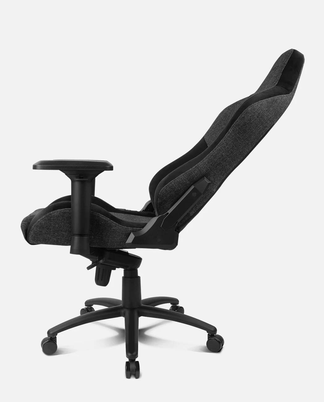 Una silla gaming negra y gris se muestra de lado. La silla tiene respaldo alto y reposabrazos, sobre fondo blanco.