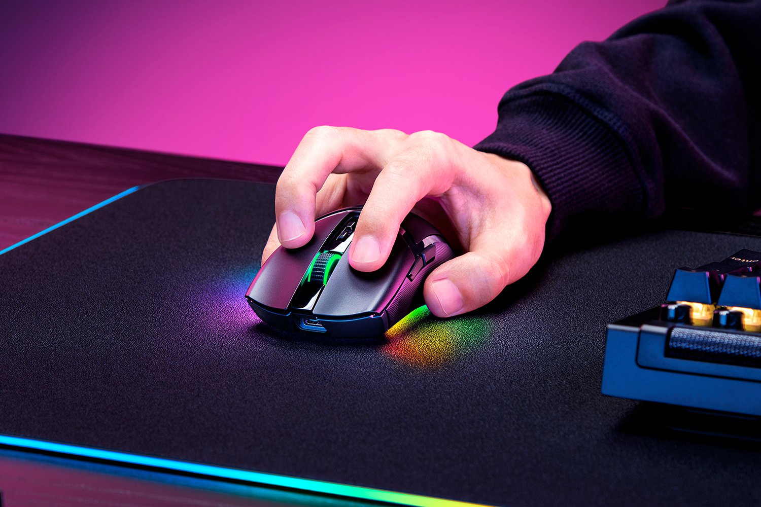 Eine Hand benutzt eine schwarze und grüne Gaming-Maus auf einem schwarzen Mauspad mit RGB-Lichtern.