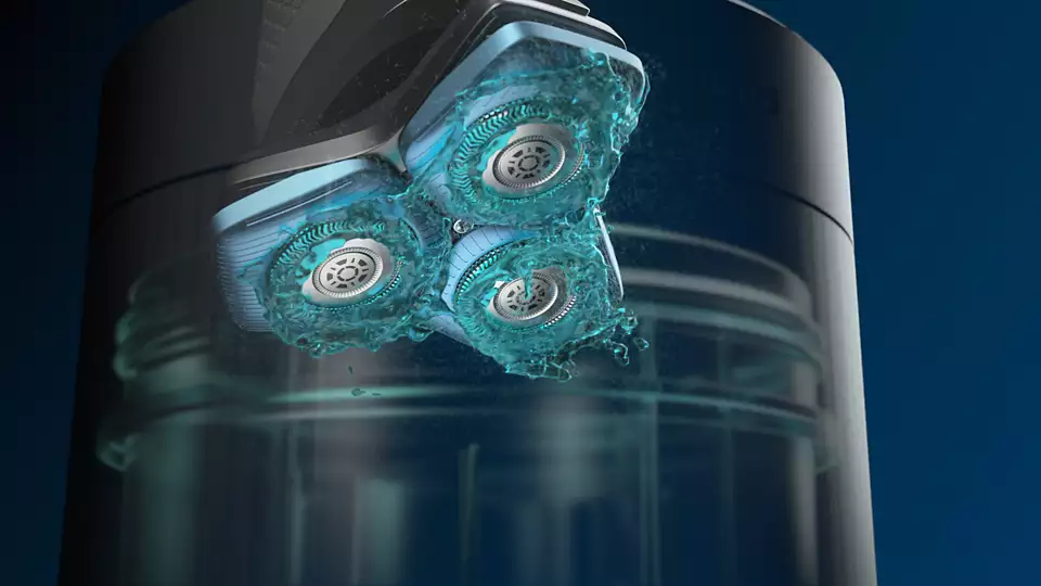 Elektrorasierer-Rasierköpfe werden mit Wasser gespült, blauer Hintergrund.