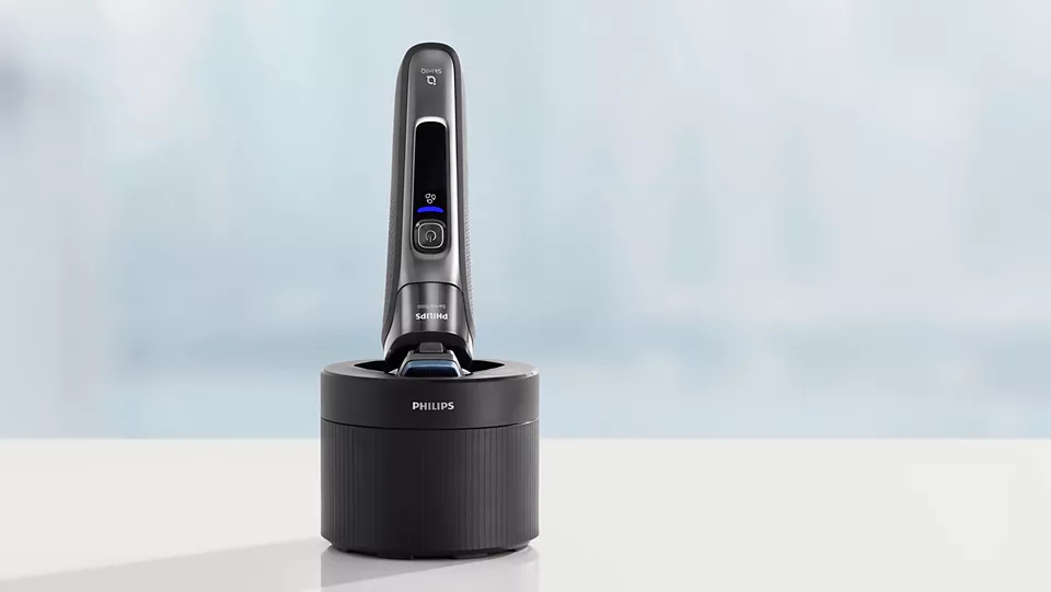Ein schwarzer und grauer elektrischer Philips-Rasierer in einer schwarzen Ladestation auf einer weißen Oberfläche.
