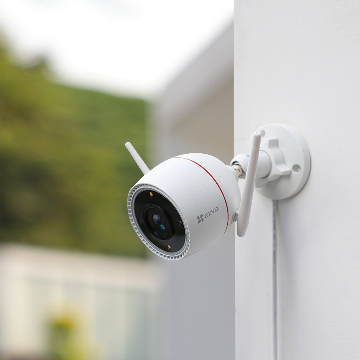 White security camera mounted on a wall. It has two antennas and a red accent.