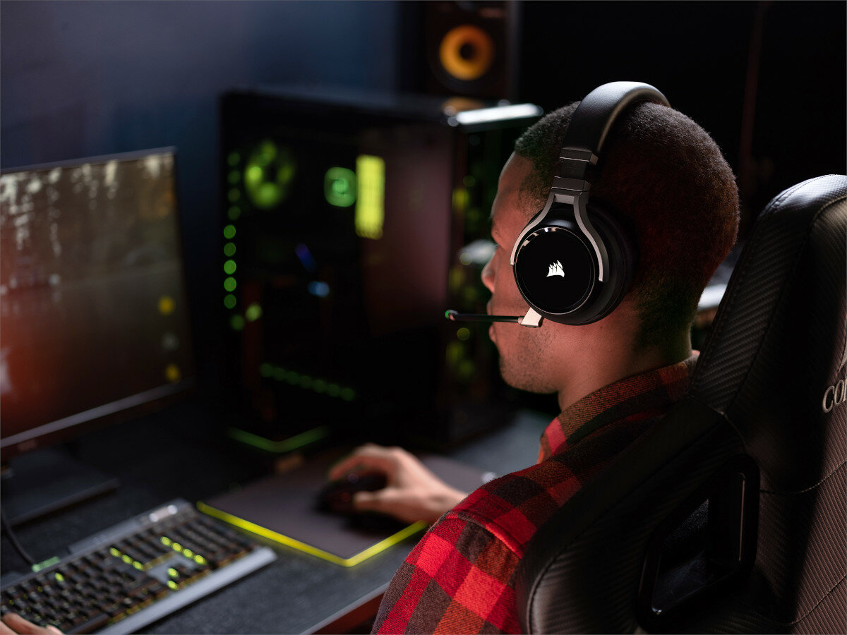 Mężczyzna w słuchawkach z mikrofonem siedzi przy komputerze. Skupia się na ekranie.