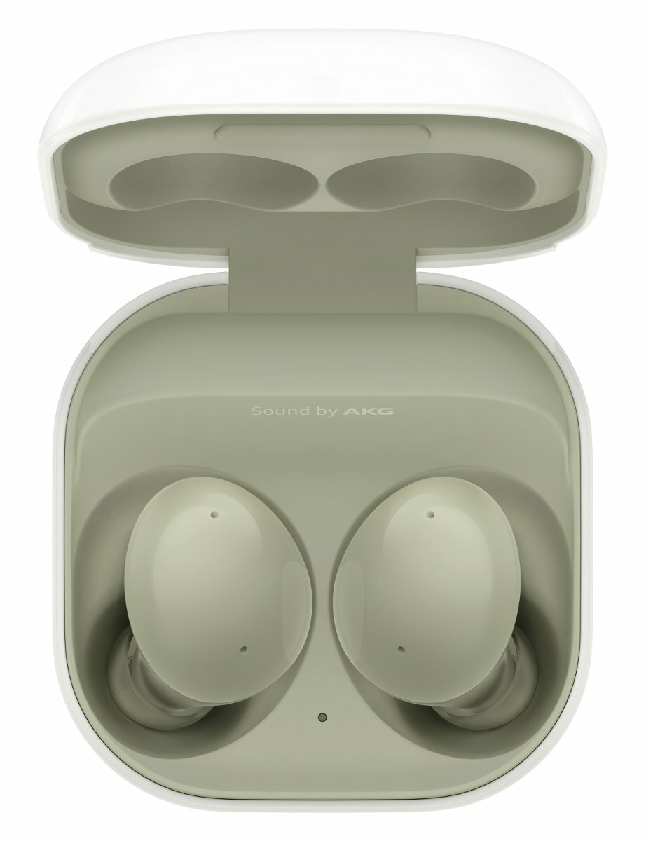 Białe i zielone słuchawki AKG w otwartym etui ładującym. Białe tło.