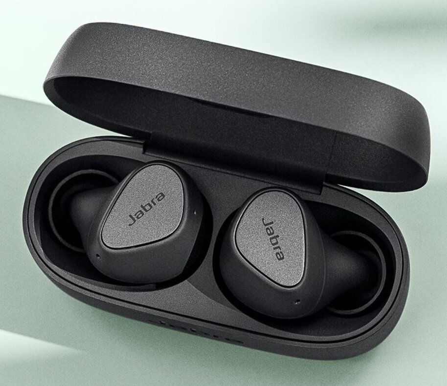 Czarne słuchawki Jabra w otwartym etui ładującym, na jasnozielonej powierzchni.