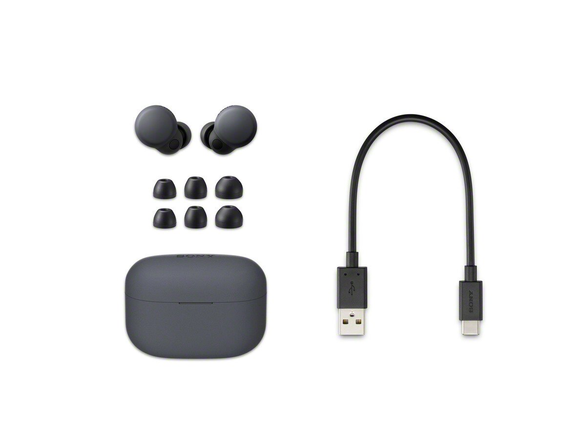 Słuchawki, etui ładujące i kabel USB na białej powierzchni. Słuchawki są ciemnoszare.