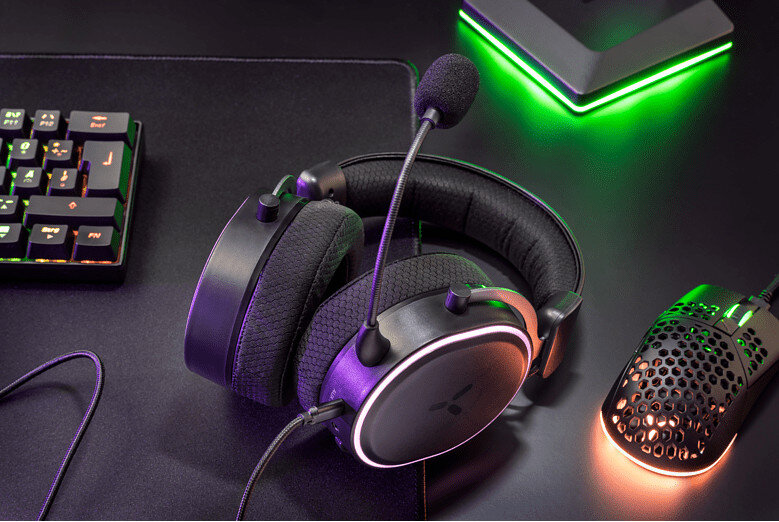 Konfiguracja do gier ze słuchawkami, myszą i klawiaturą na biurku. Oświetlenie jest kolorowe.
