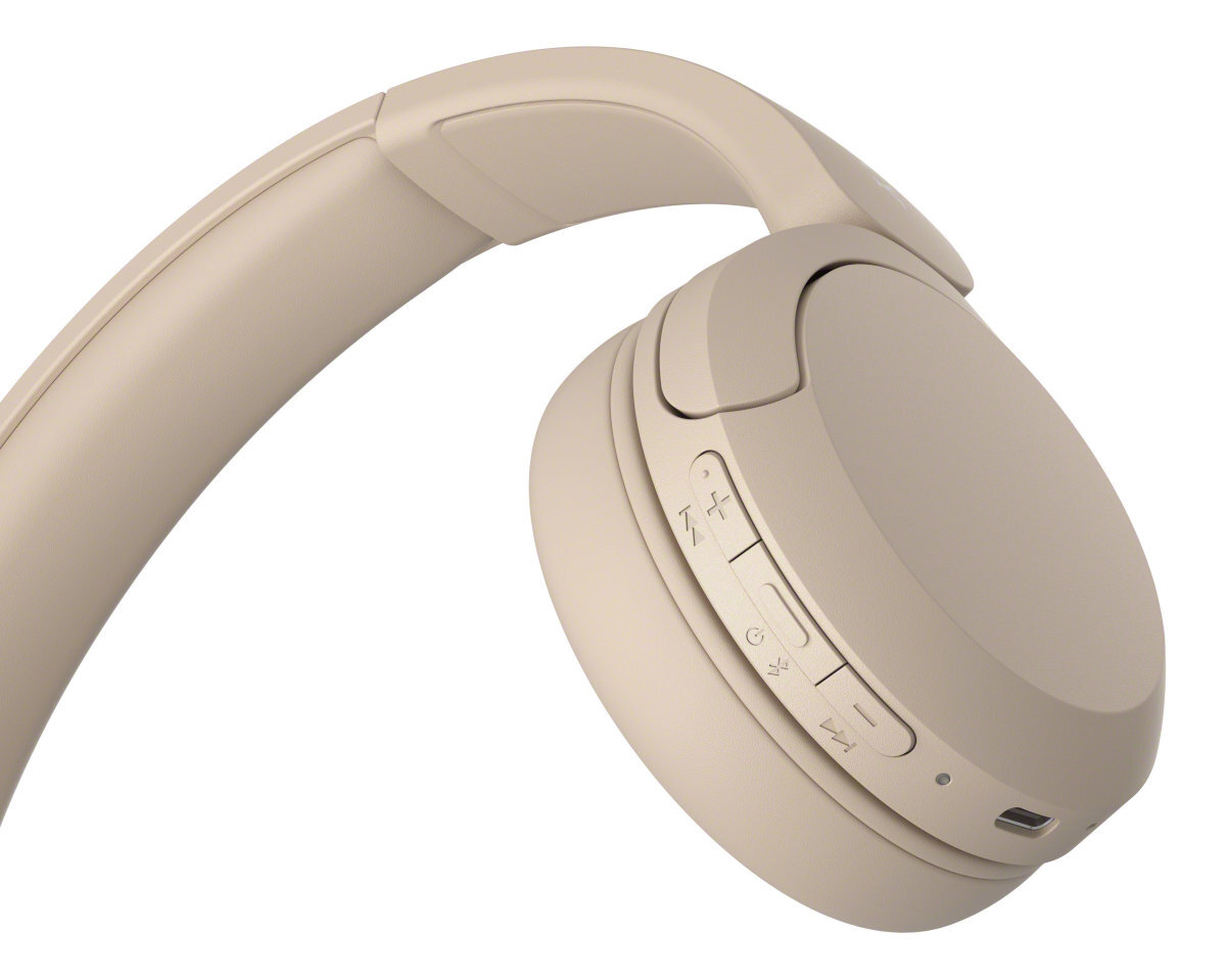 Zbliżenie beżowych słuchawek, pokazujące przyciski głośności i port USB-C.