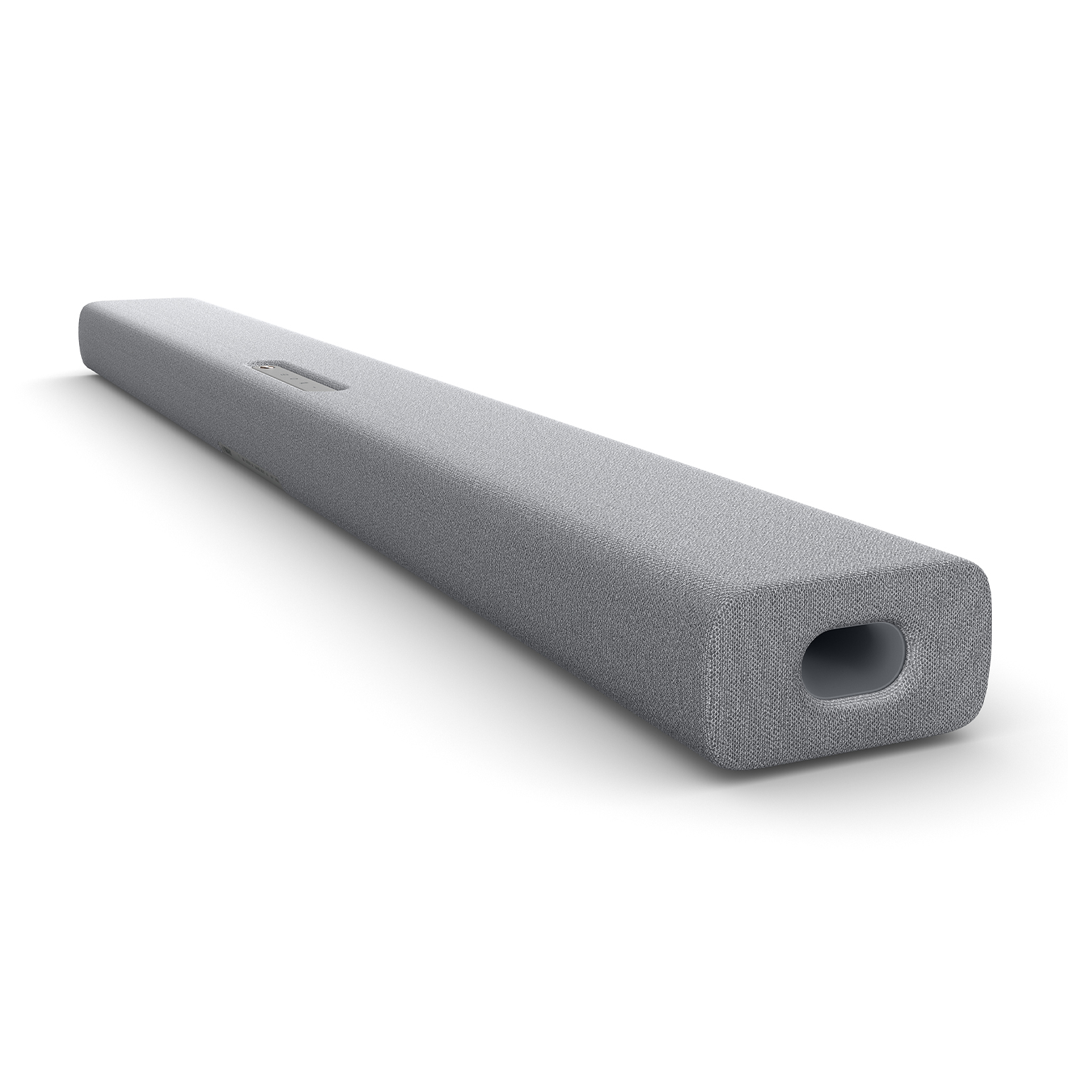Una soundbar grigia con rivestimento in tessuto, su superficie bianca, con un foro all'estremità destra.