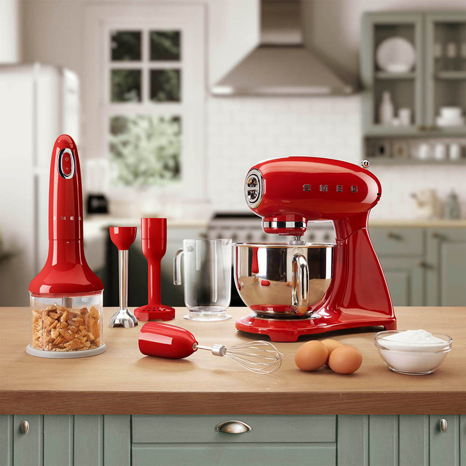 Mixer da cucina rosso con accessori. Include un frullatore e uova su un piano di lavoro in legno.