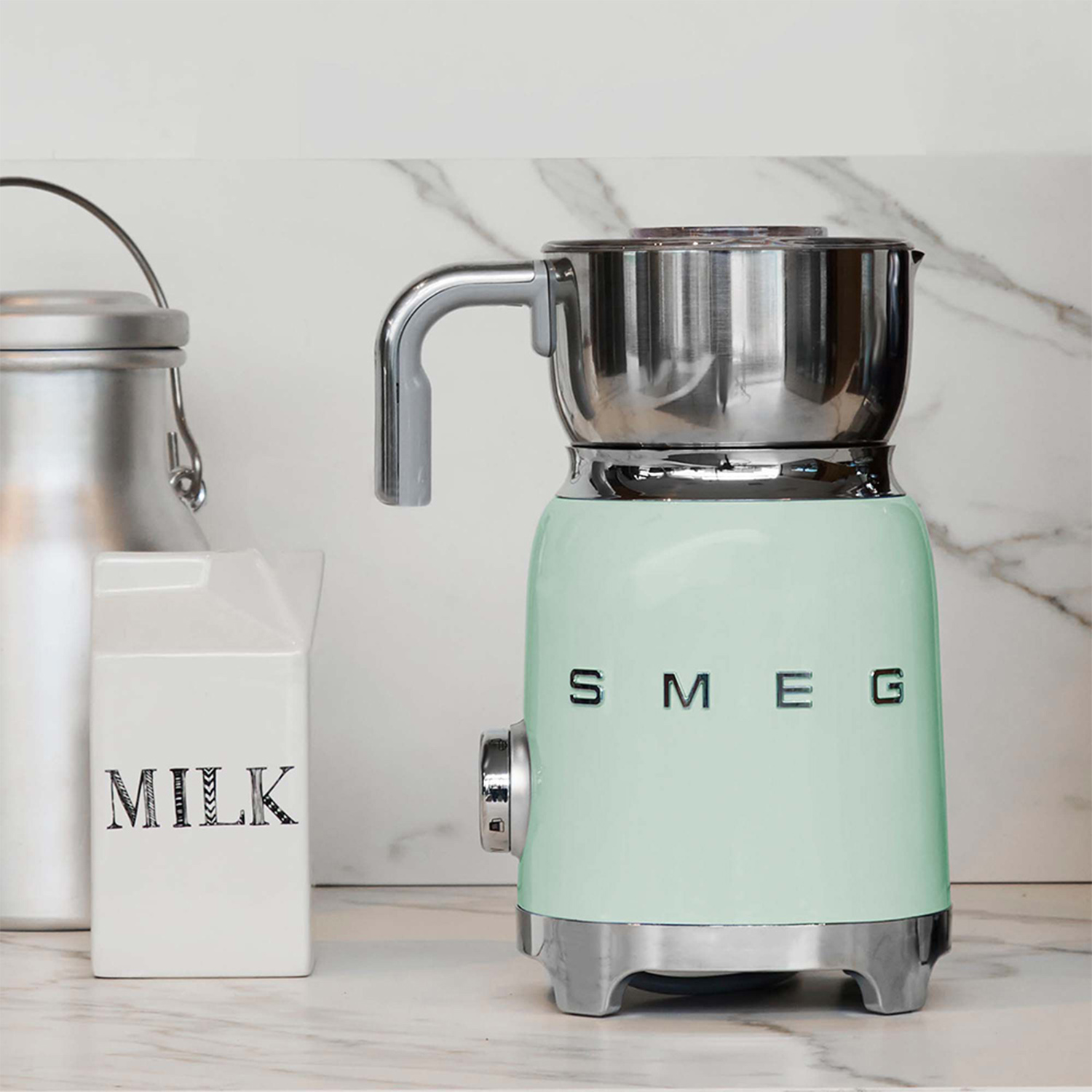 Montalatte SMEG verde menta con accessori, su un piano di lavoro in marmo.