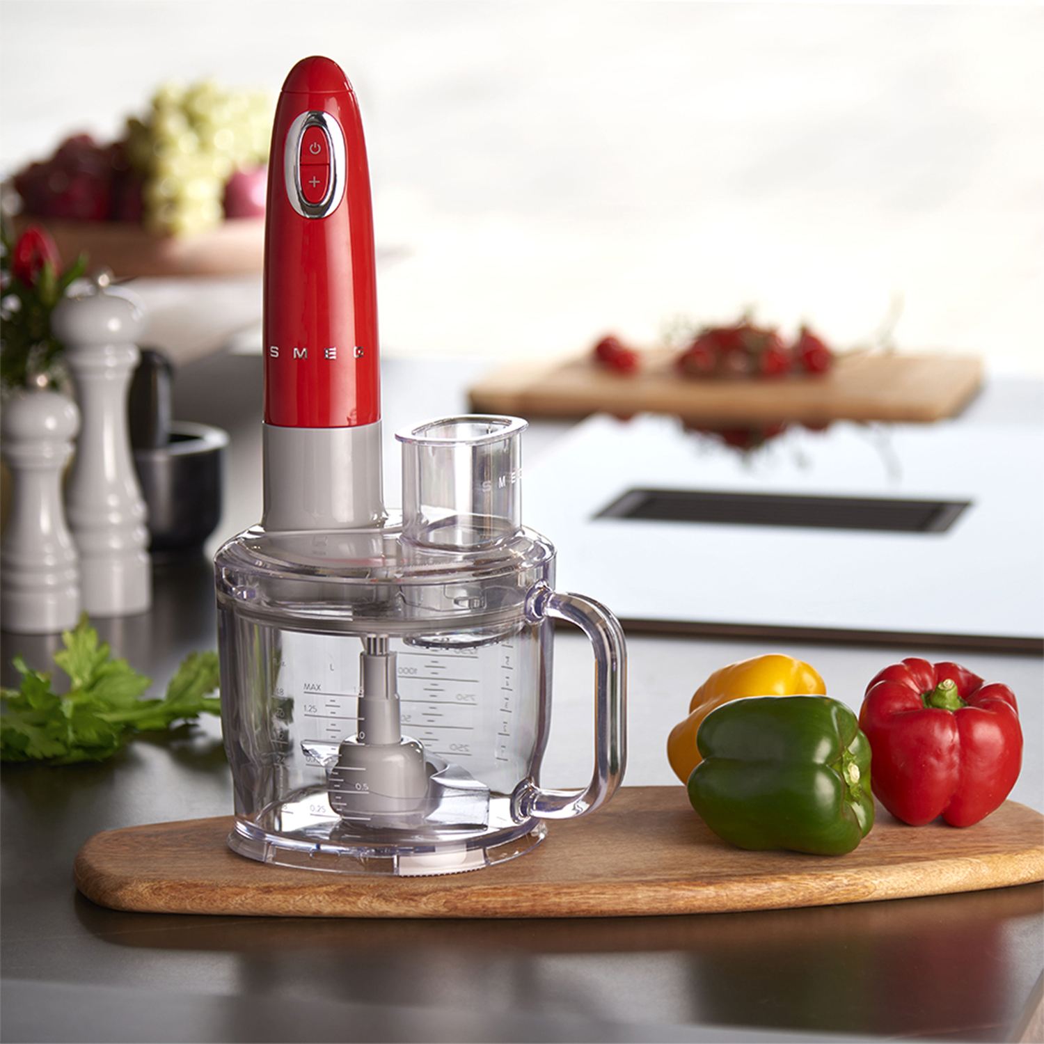 Un robot da cucina Smeg rosso con una ciotola per tritare e verdure su un tagliere.