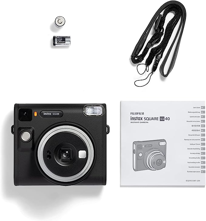 Una cámara instantánea negra con accesorios: pilas, correa y manual. La cámara es Fujifilm Instax SQ40.