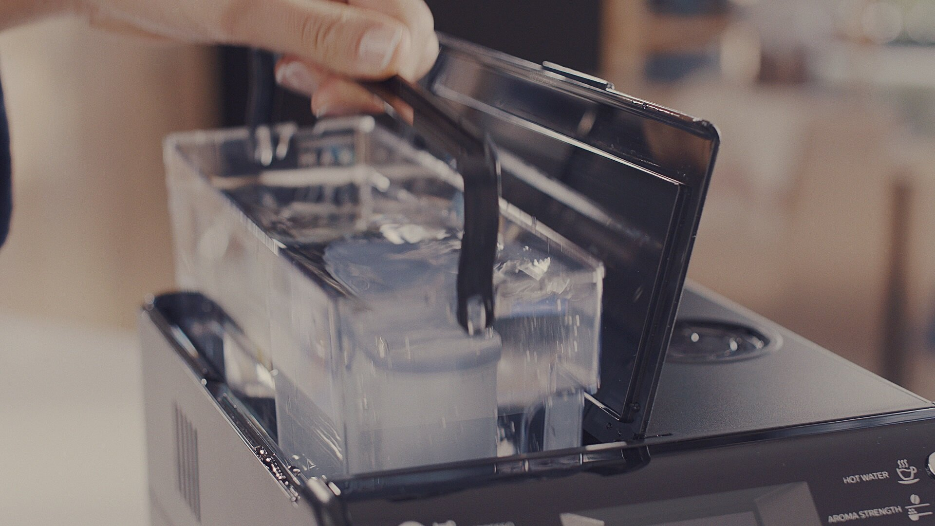 Osoba dodaje wodę do ekspresu do kawy. Czarna maszyna. Wnętrze.