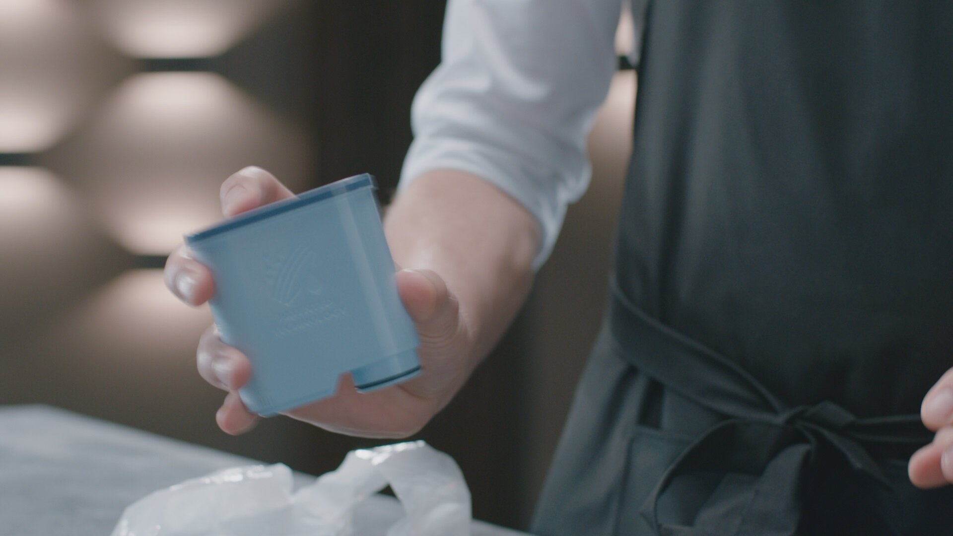 Osoba trzymająca niebieski kubek filtra w pobliżu torby.