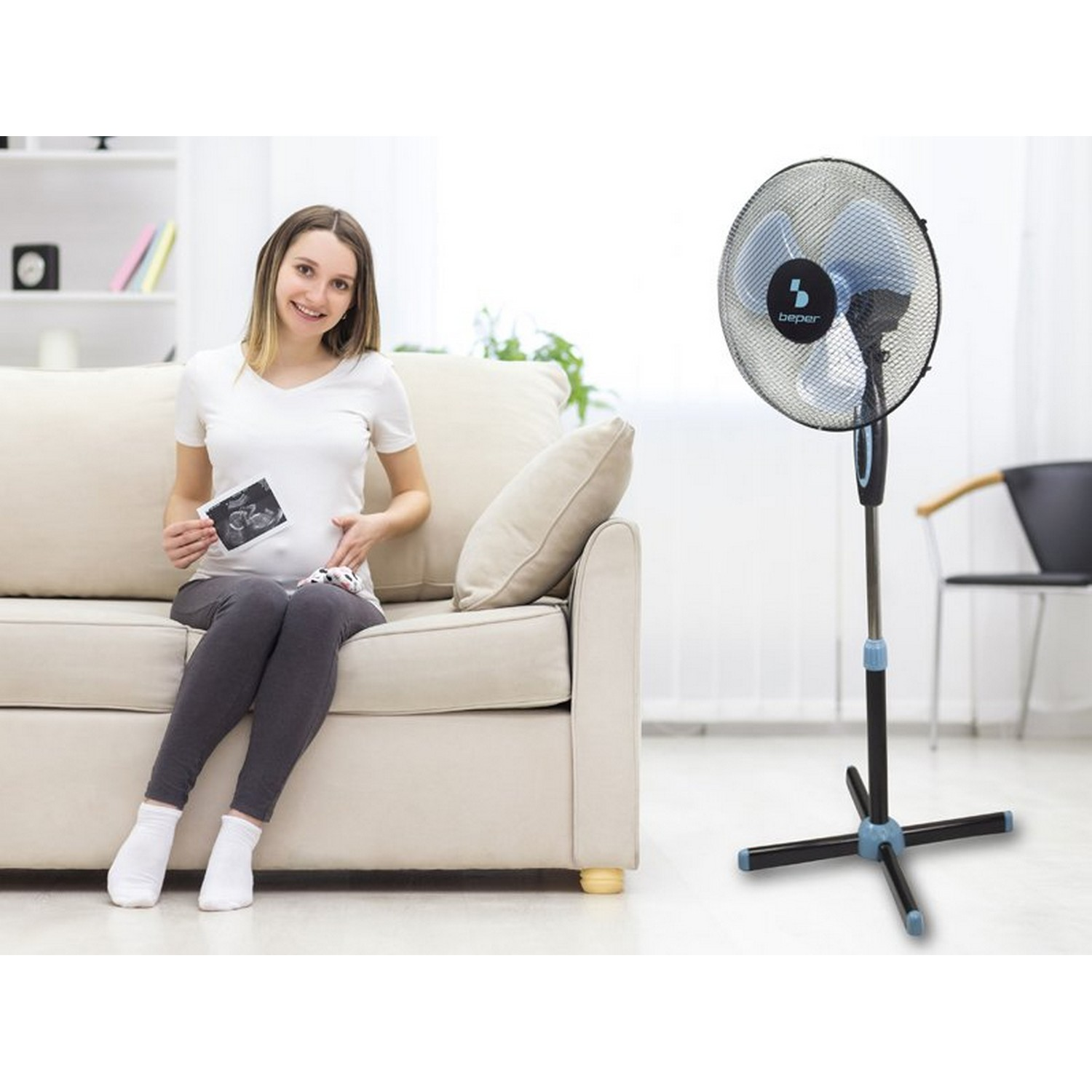 Femme enceinte tenant une photo d'échographie, assise avec un ventilateur.