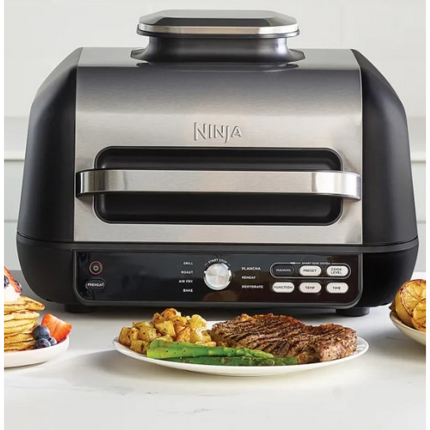 A black and silver Ninja grill with cooked food on the counter.
