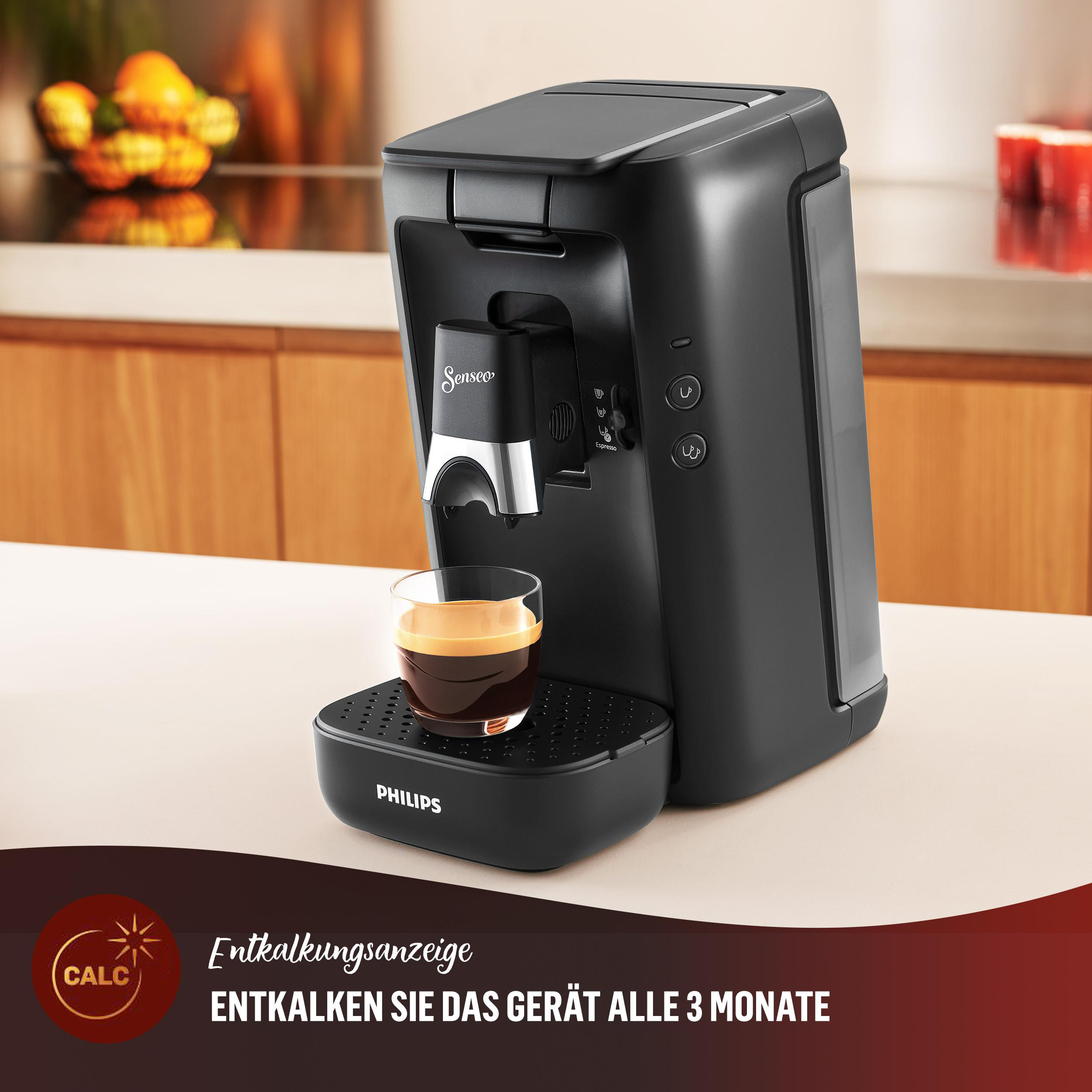 Schwarze Kaffeemaschine mit Kaffeeglas. Text zeigt Entkalken an.