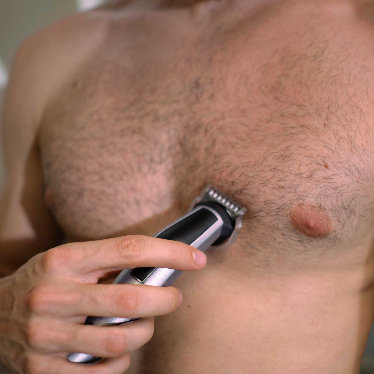 Osoba używająca elektrycznej maszynki do przycinania na klatce piersiowej. Włosy są widoczne.