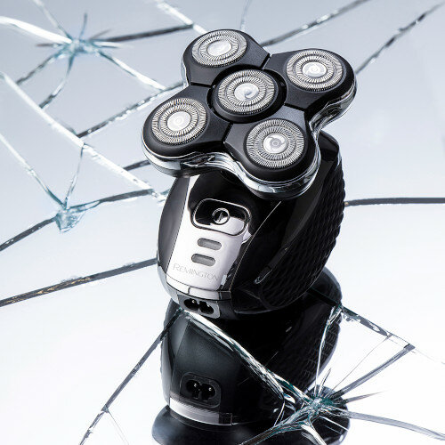 Czarna golarka elektryczna na odblaskowej powierzchni z potłuczonym szkłem.