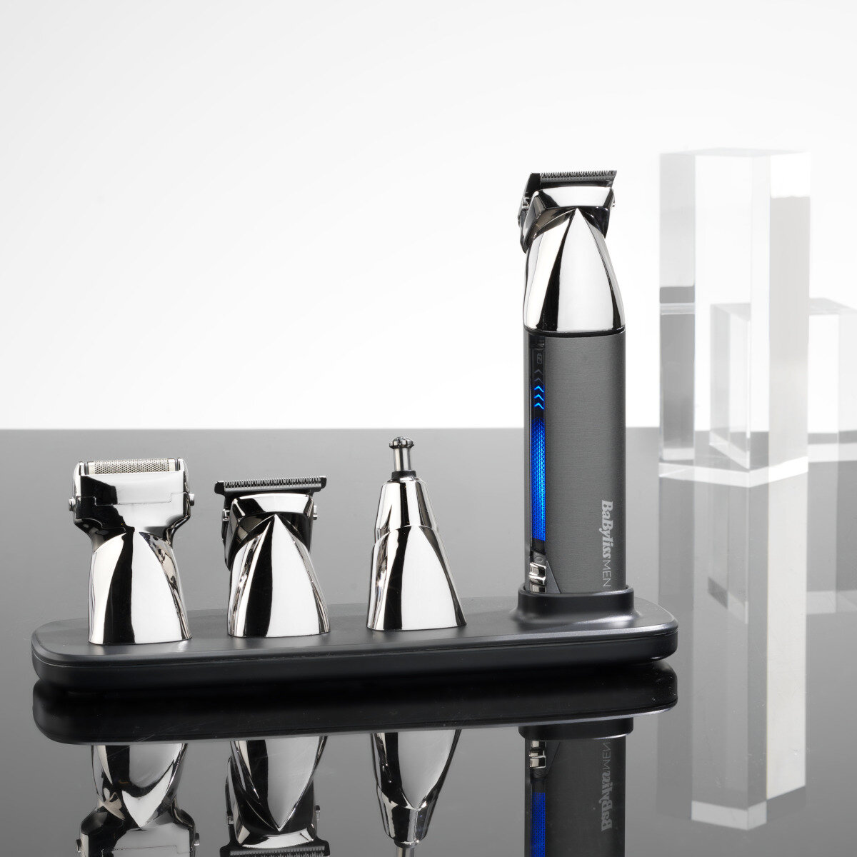 Zestaw do pielęgnacji męskiej z trymerem i nasadkami, z niebieskim światłem, odbijającym się na powierzchni.