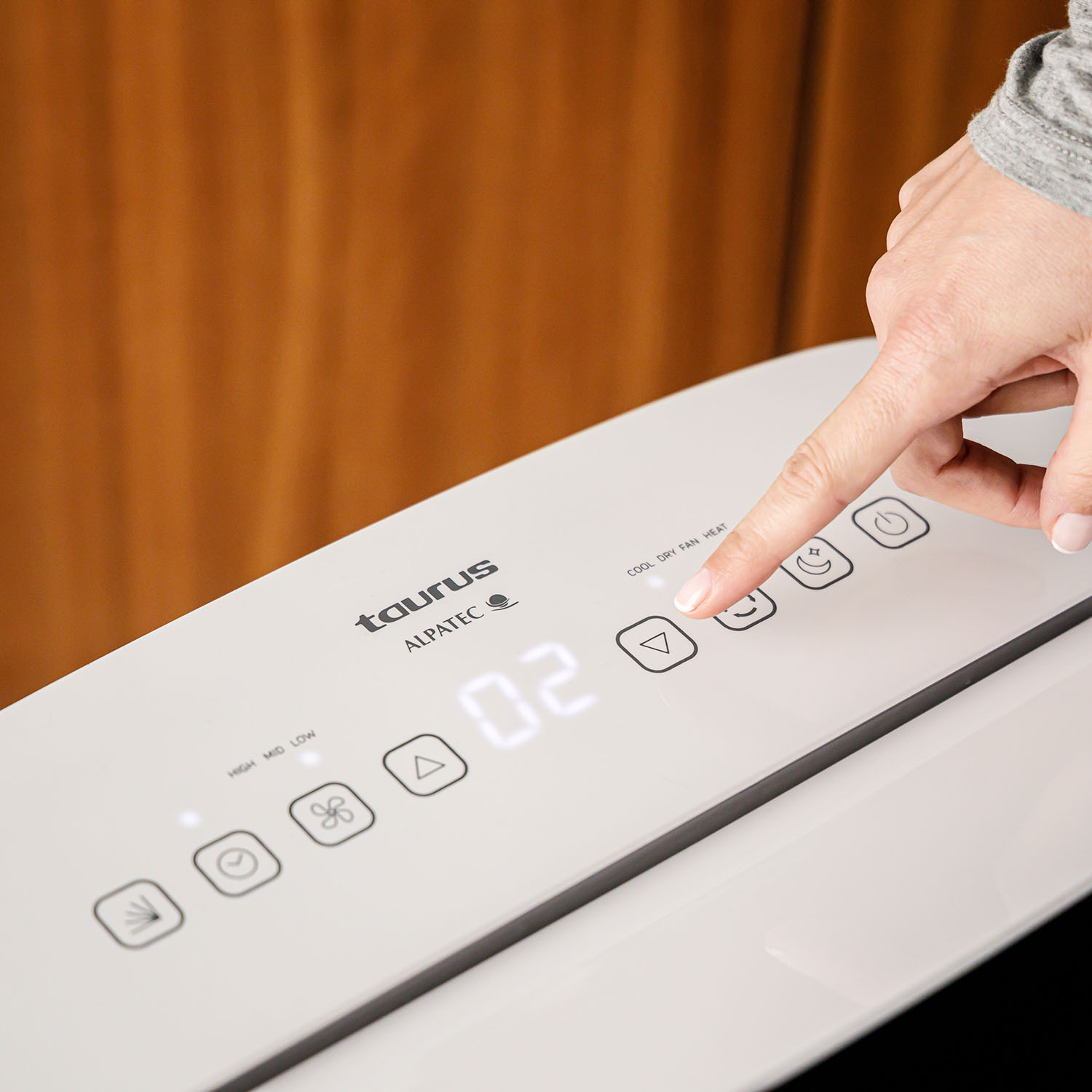 Una mano presionando el botón 'abajo' en un dispositivo Taurus Alpatec blanco.
