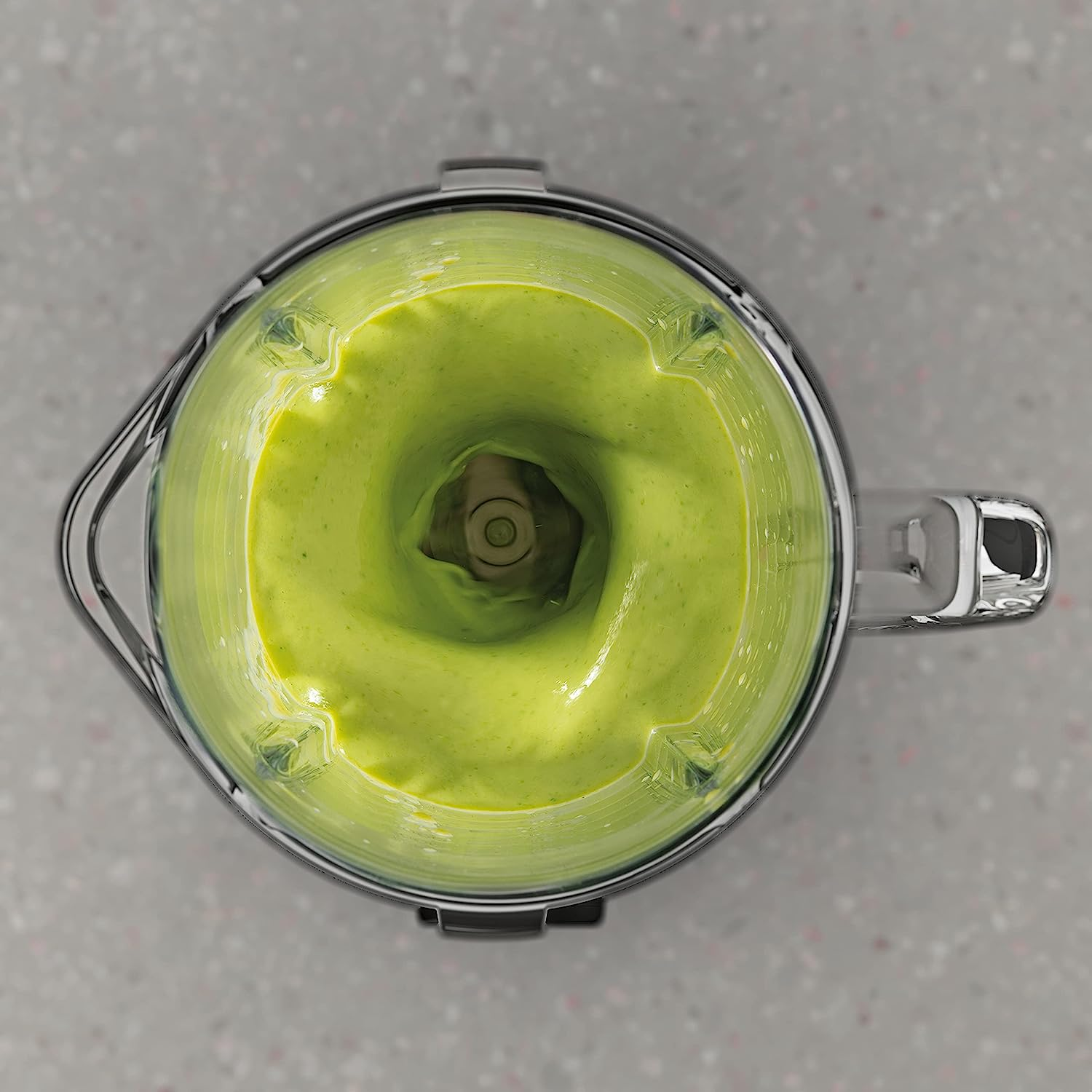 İçinde yeşil smoothie olan bir blender, yukarıdan görünüm. Gri yüzey.