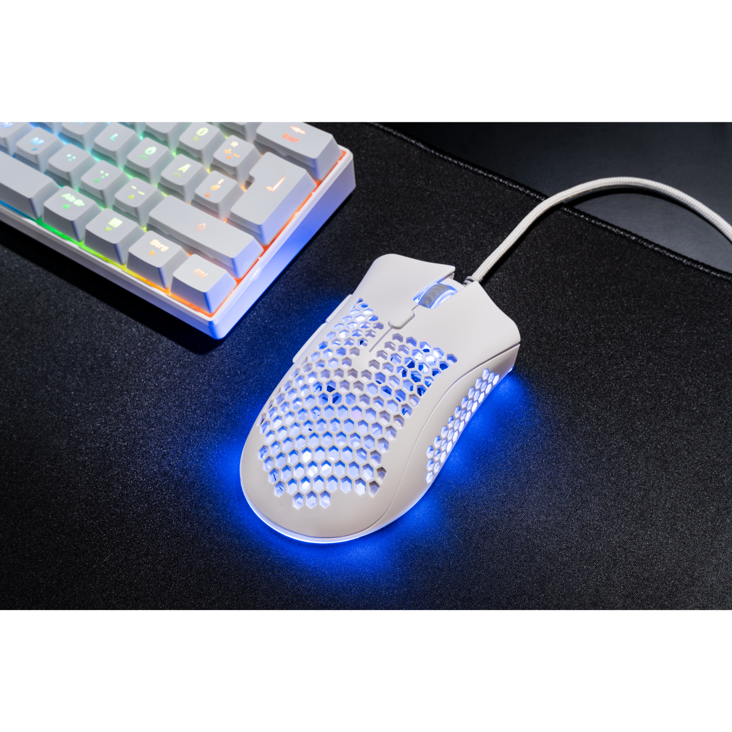 Witte gamingmuis met een honingraatontwerp en blauwe LED-verlichting. Een toetsenbord staat op de achtergrond.