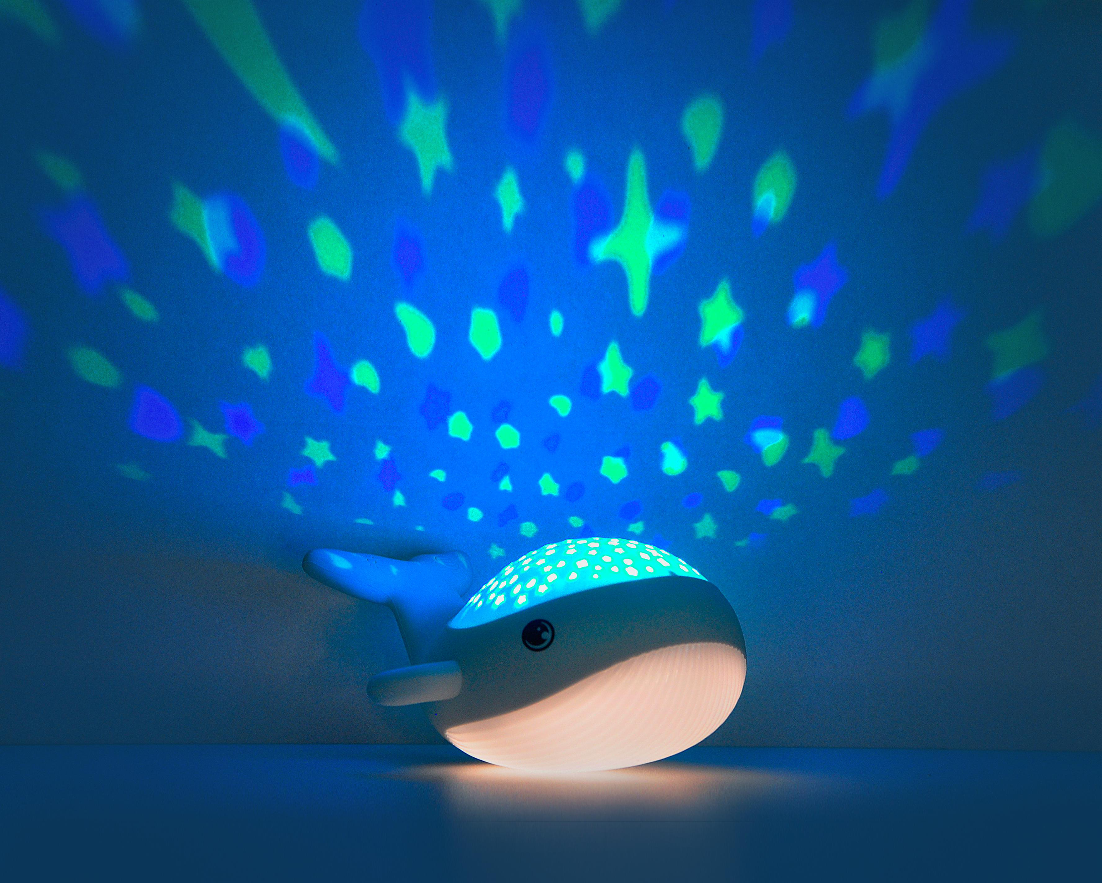 Ein walförmiges Nachtlicht projiziert blaue und grüne Sterne an die Decke. Das Licht ist an.