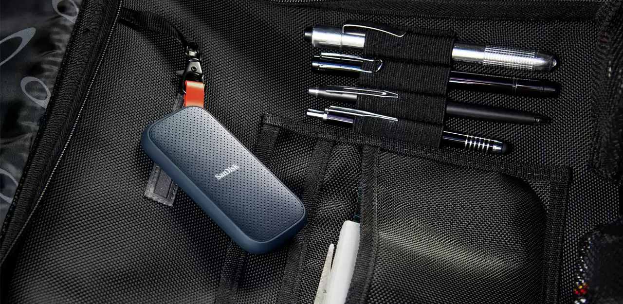 Geöffnete schwarze Tasche, Stifte in Haltern, eine blaue externe Festplatte von SanDisk.
